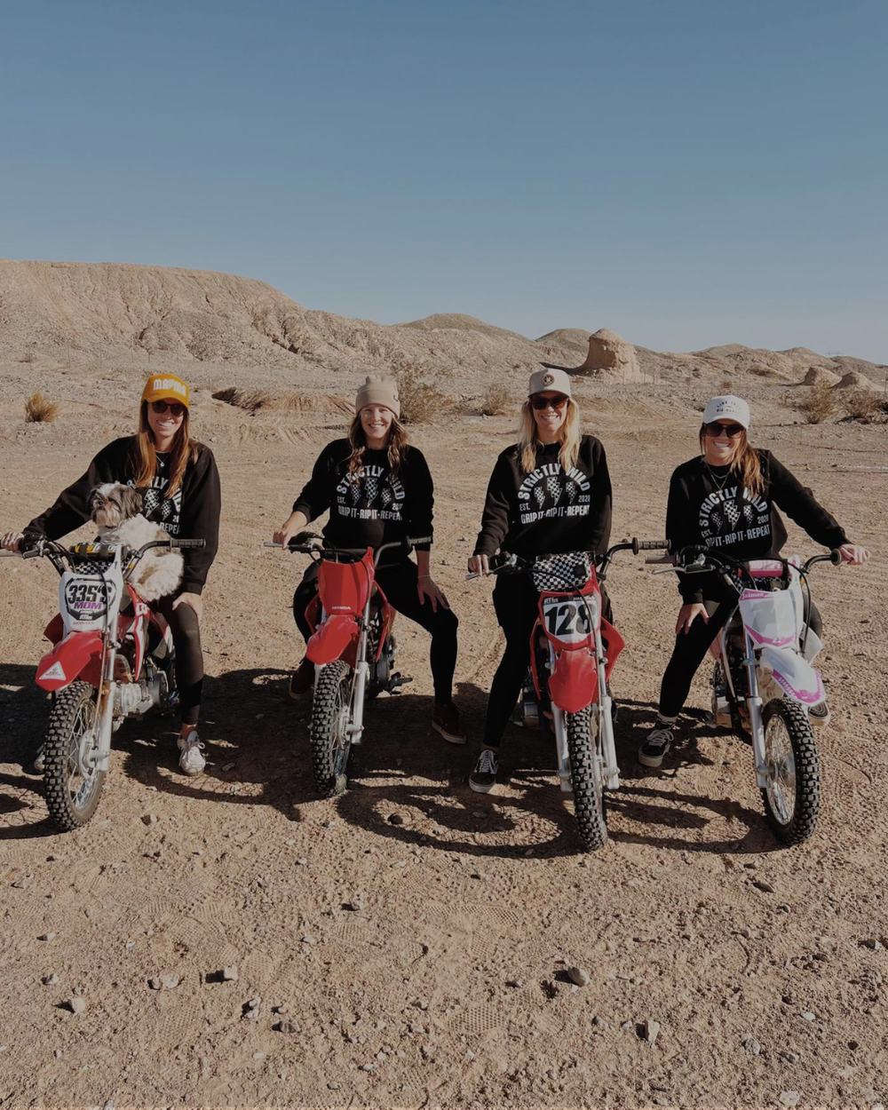 Four people on dirt bikes in a desert setting