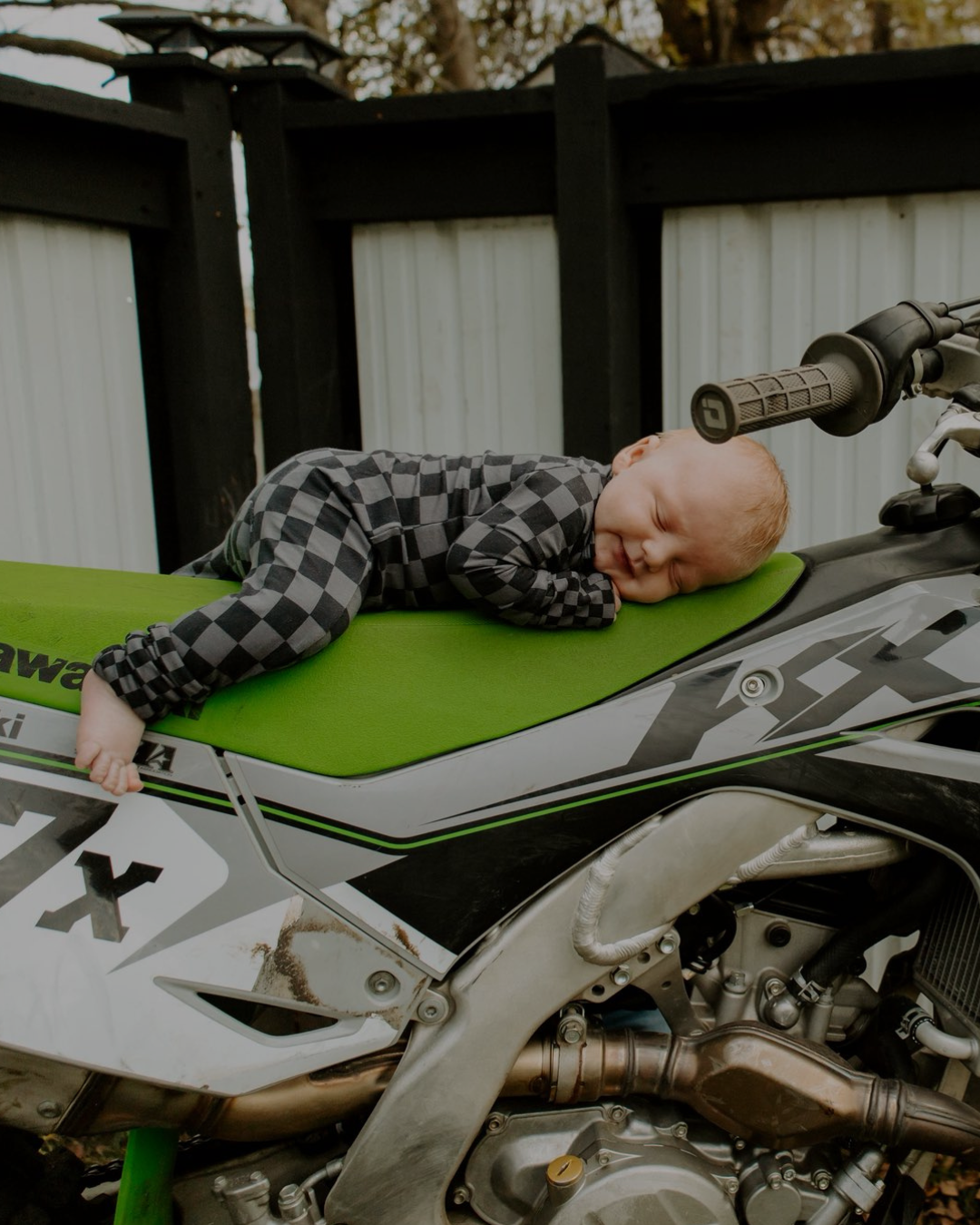 Child lying on a Kawasaki motorcycle with a blurred background