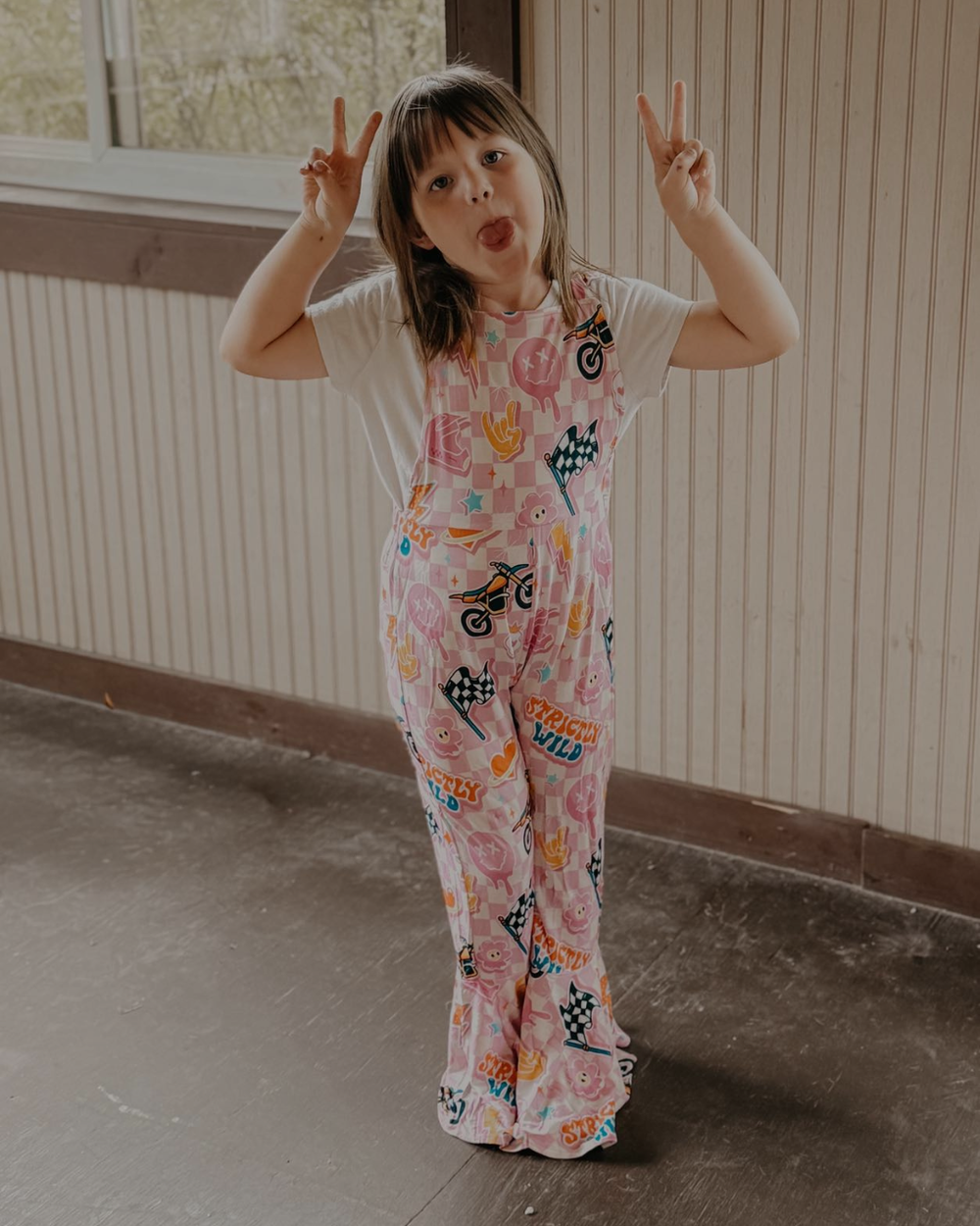 Child wearing a colorful patterned outfit standing indoors.