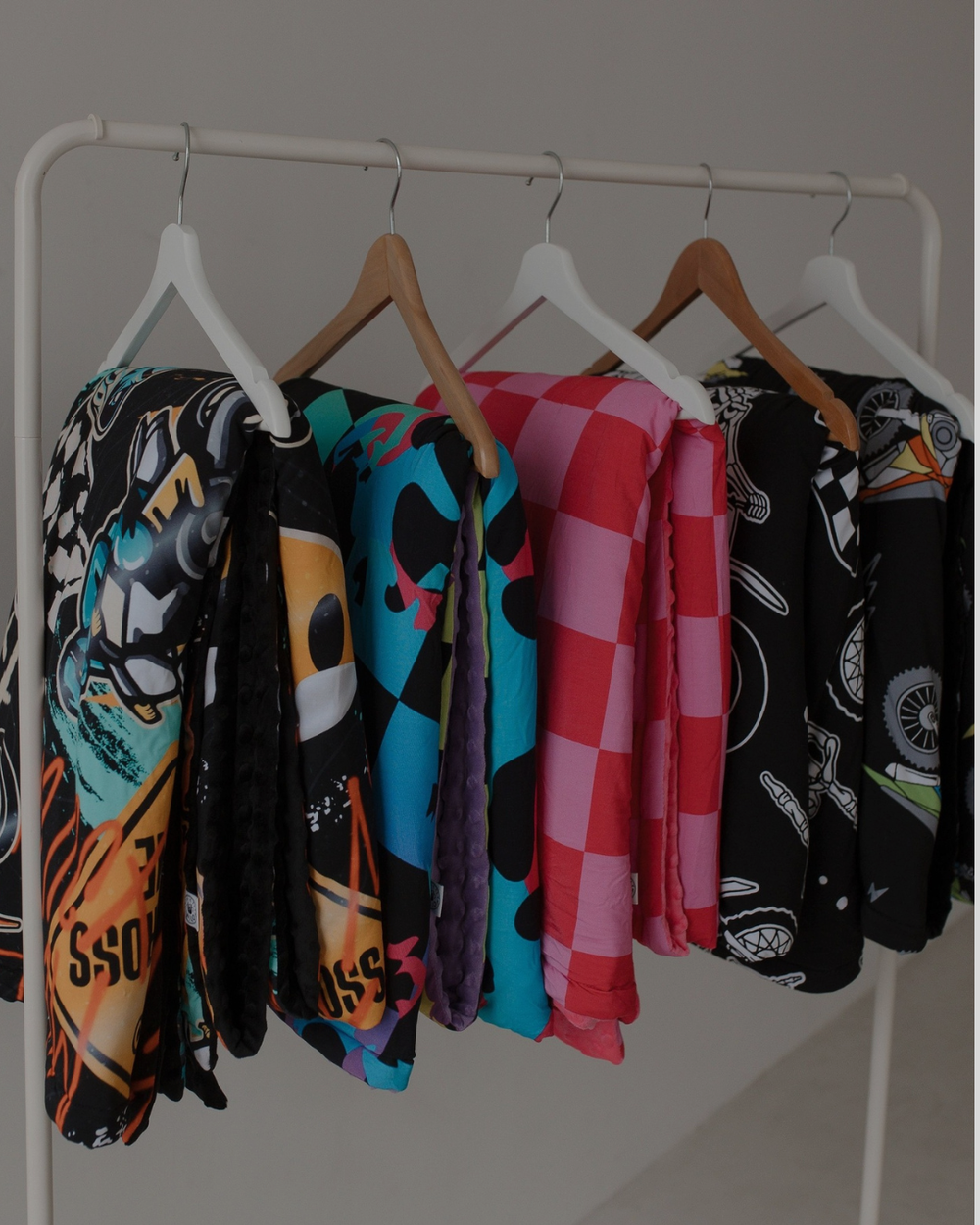 Colorful towels hanging on a rack against a plain background