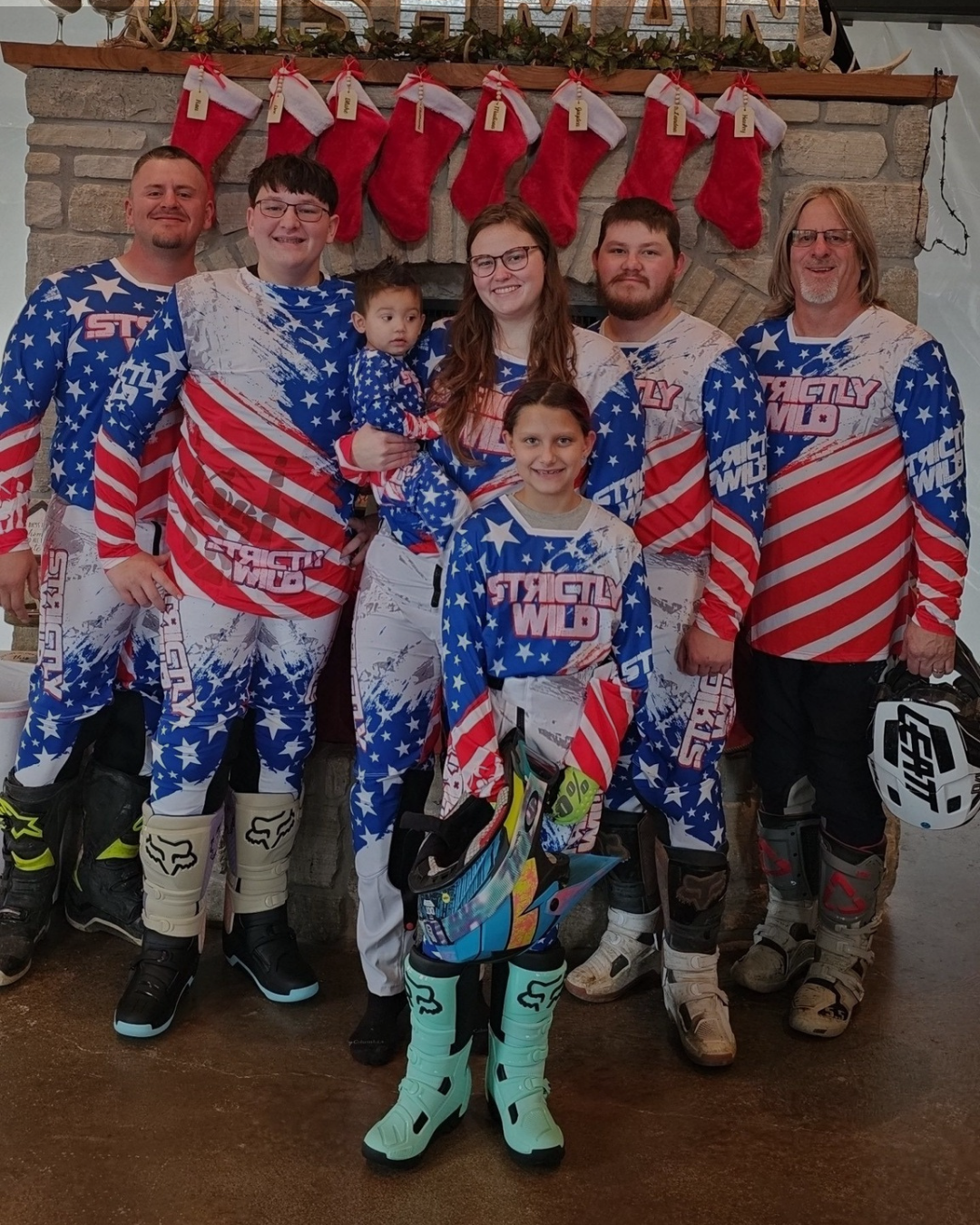 Family in motocross gear posing in front of a fireplace with stockings.